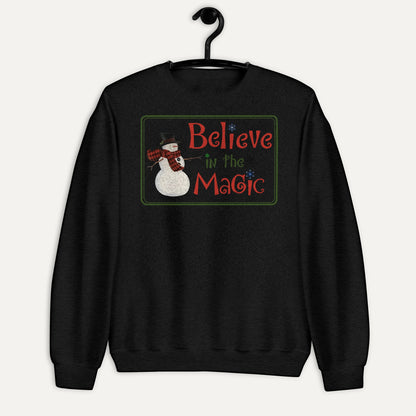 Believe In The Magic Unisex Long Sleeve Sweatshirt in Black, on hanger