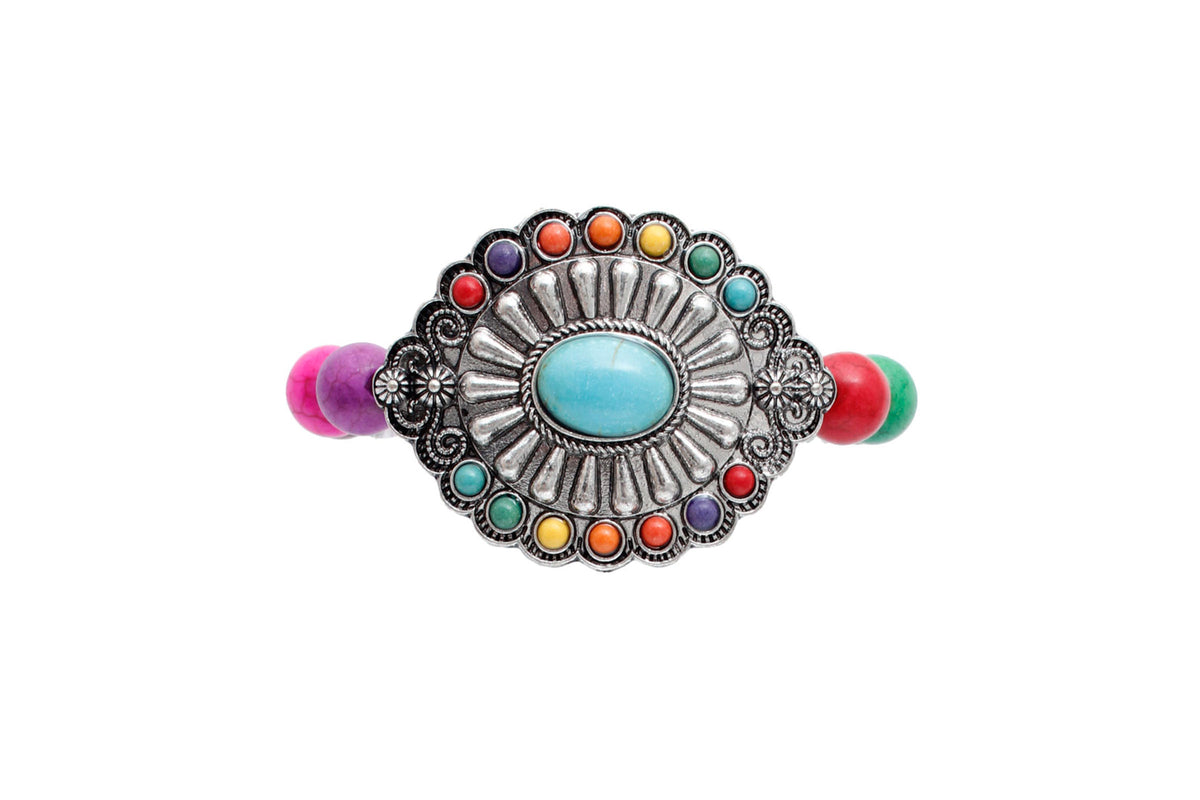 Close-up of a burnished silver-tone concho with a turquoise-colored center and multicolor stones