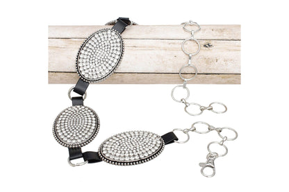 Close-up of rhinestone oval conchos and chain links on a wood background