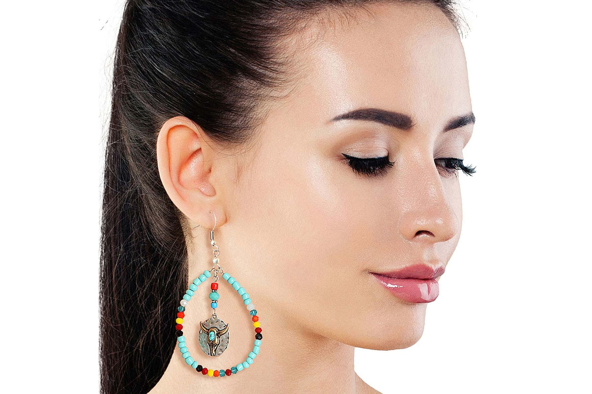 Model wearing turquoise-colored beaded teardrop earrings with a longhorn charm