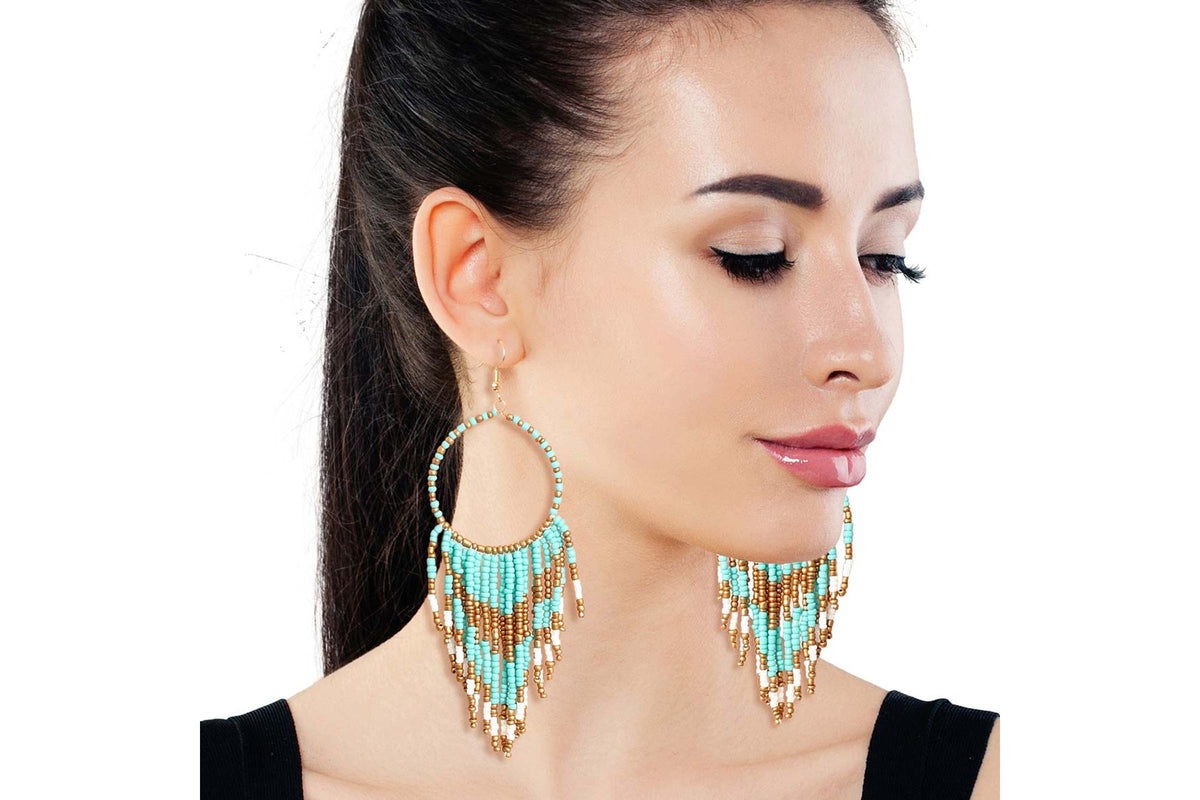 Model wearing turquoise-colored and gold beaded fringe hoop earrings